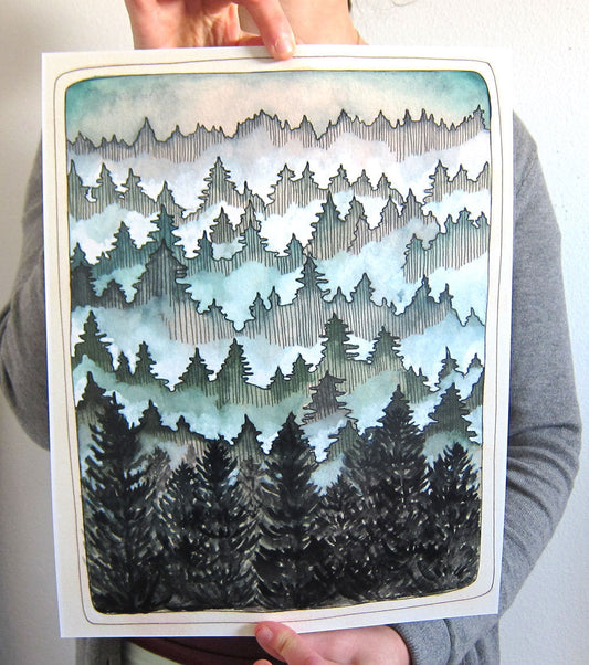 Person holding a painting of a forest landscape with trees and mountains.