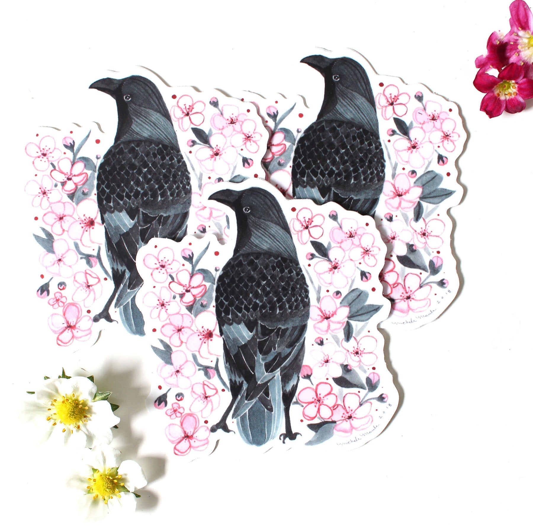 Three black birds surrounded by pink flowers on a white background