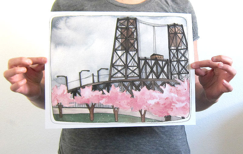 Print of Portland's Steel Bridge with pink Cherry Blossoms blooming along the waterfront. 